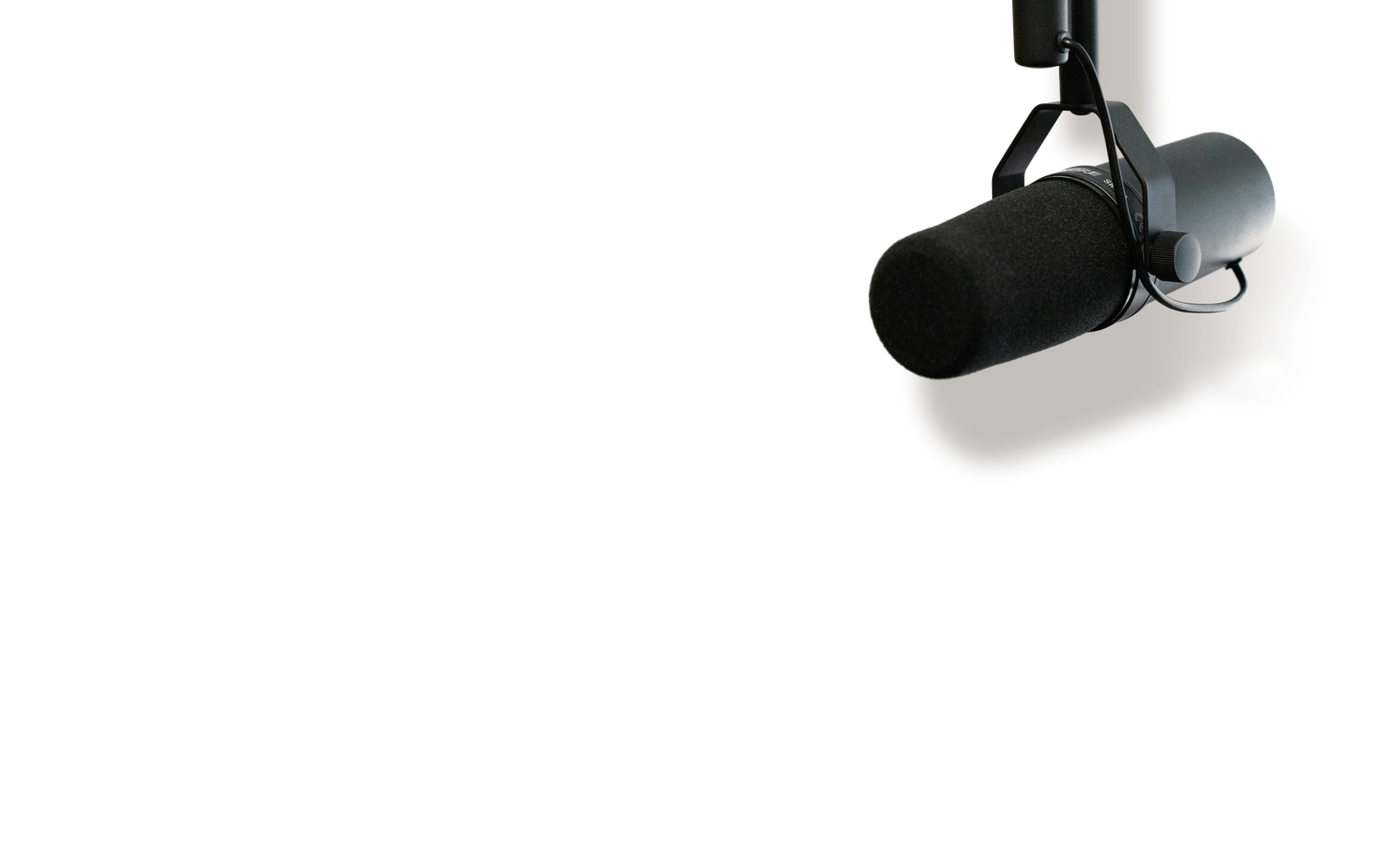 A broadcast microphone hanging from a boom arm, casting a shadow